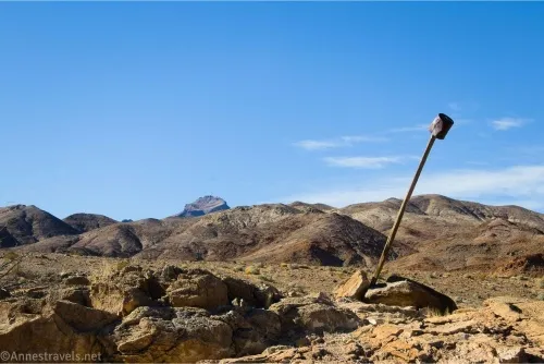In desert mountains, a rusty bucket sails atop a wooden post