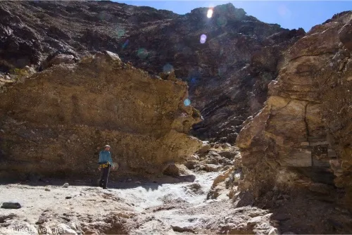 Cliffs bound a desert wash with taller mountain cliffs beyond