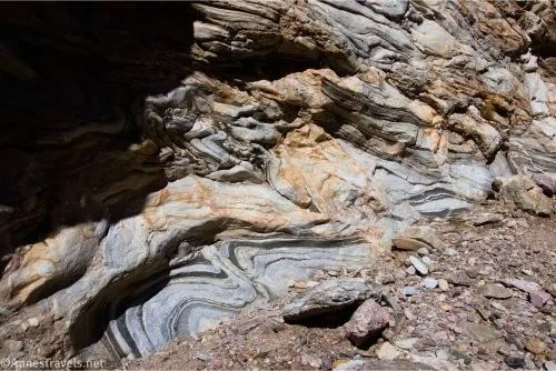 Layers of gray, black, and gold rock are curved in folds 