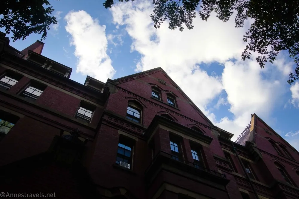 A brick building rises to the sky filled with white clouds