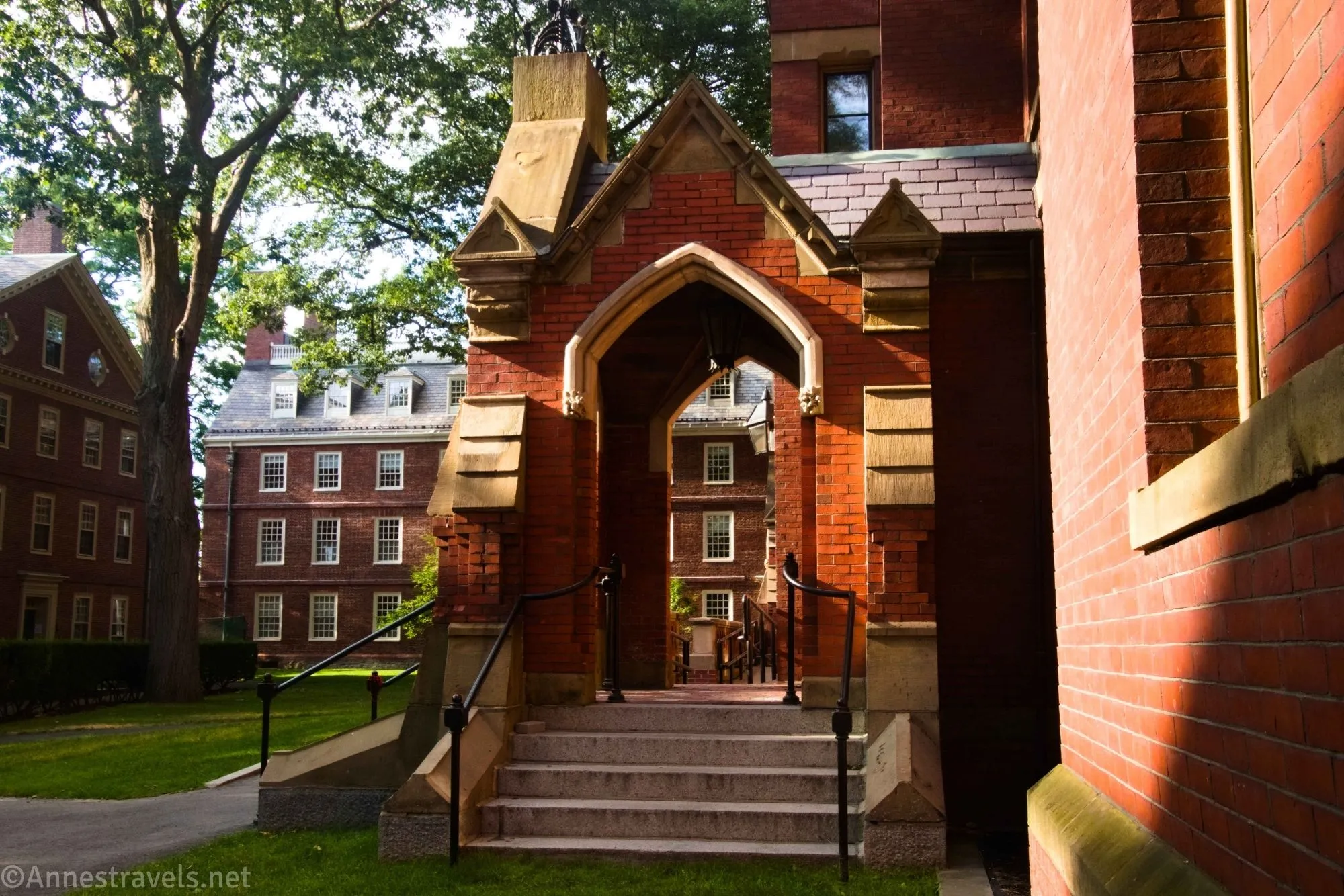 A brick entryway on a red brick building with more red brick buildings and a tree beyond