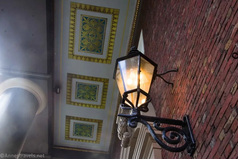 A lamp on a brick wall and blue and gold decorations on the white ceiling