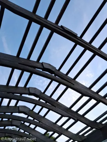 Blue sky and clouds through the bars and beams of an arbor
