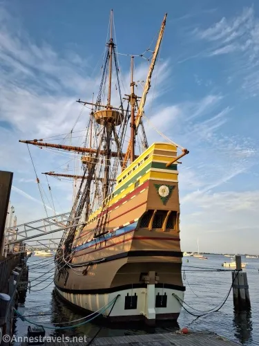 An English ship, brown with colorful trim and a white flower on its stern, with rigging, and a crow's nest
