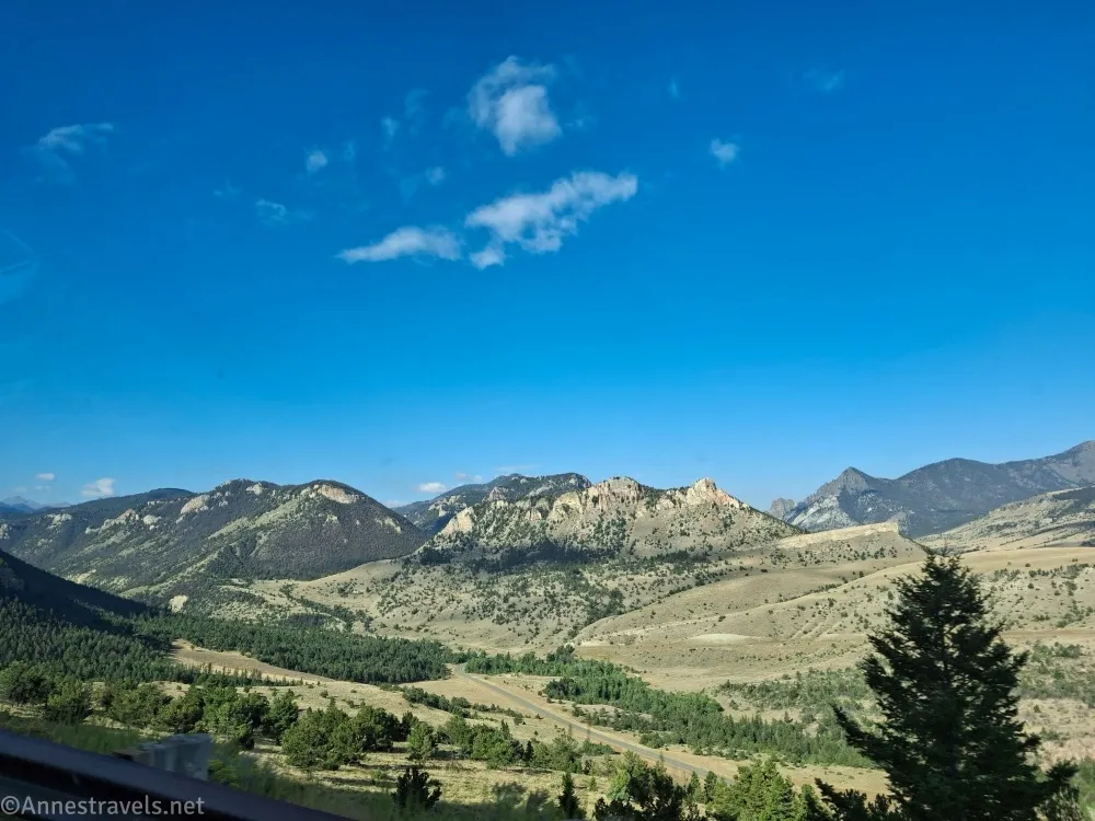 Mountains rise above a meadowed and treed valley 