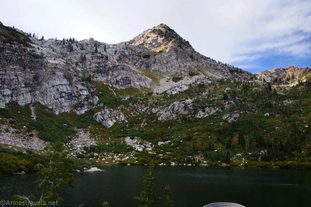 A white mountain with green slopes towers above a dusky lake