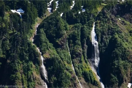 Several white waterfalls cascade down a green hillside