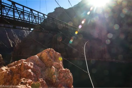A bridge rises above the photographer's head with sun streaming from above a cliff 