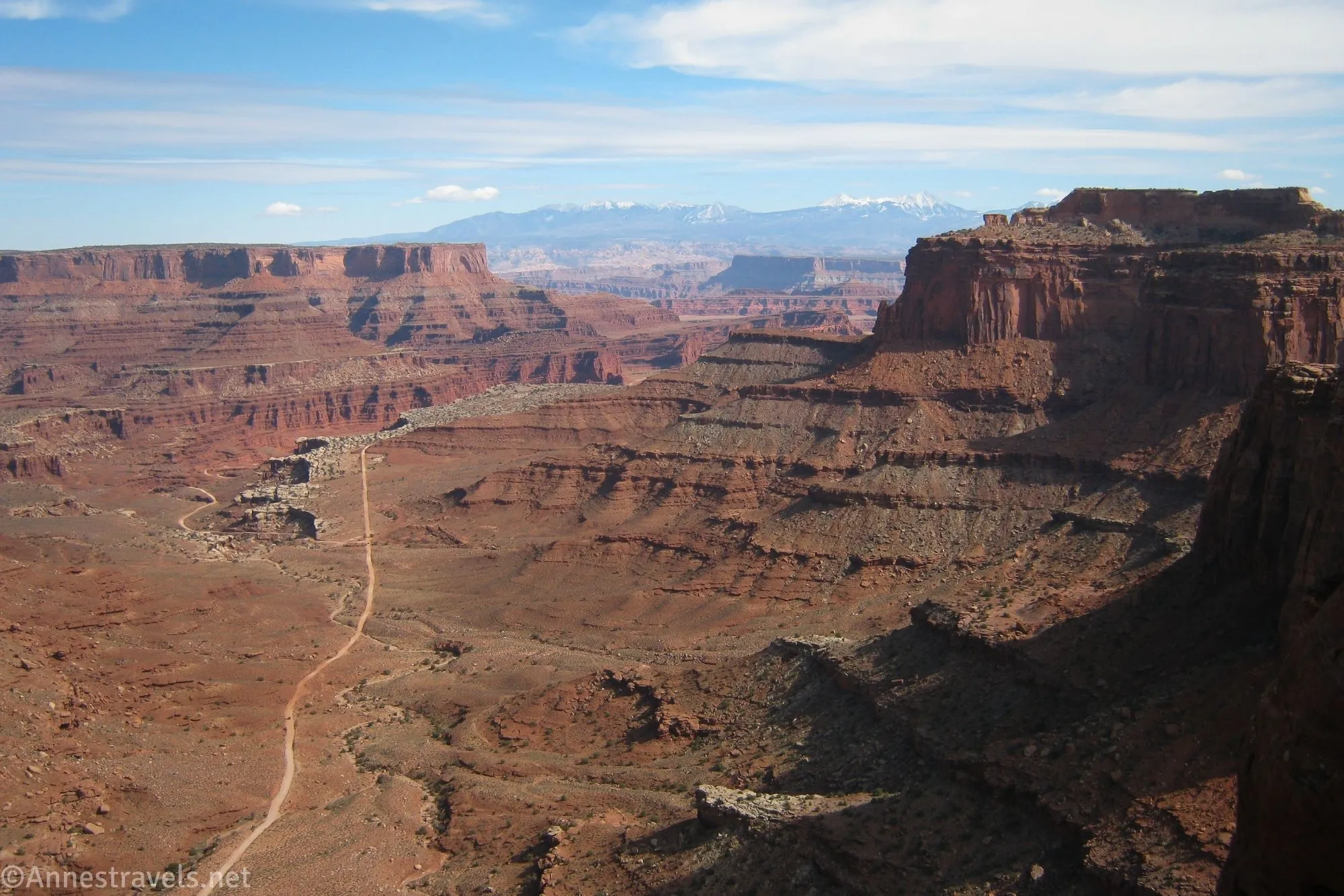 A road winds through a desert canyon surrounded by cliffs and mountains