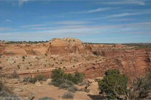 Desert cliffs rise to a slightly cloudy blue sky
