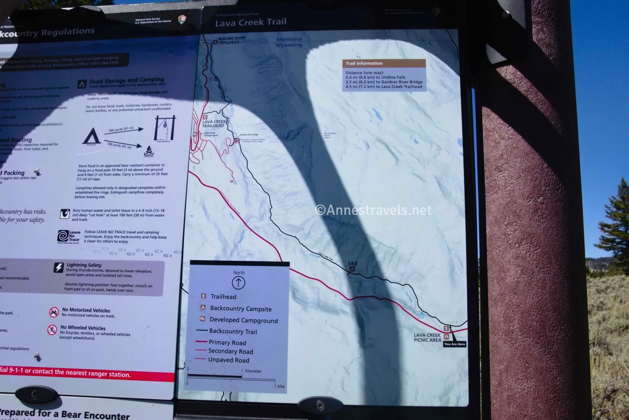 A trail sign with a map of the Lava Creek Trail in black and the road in red 