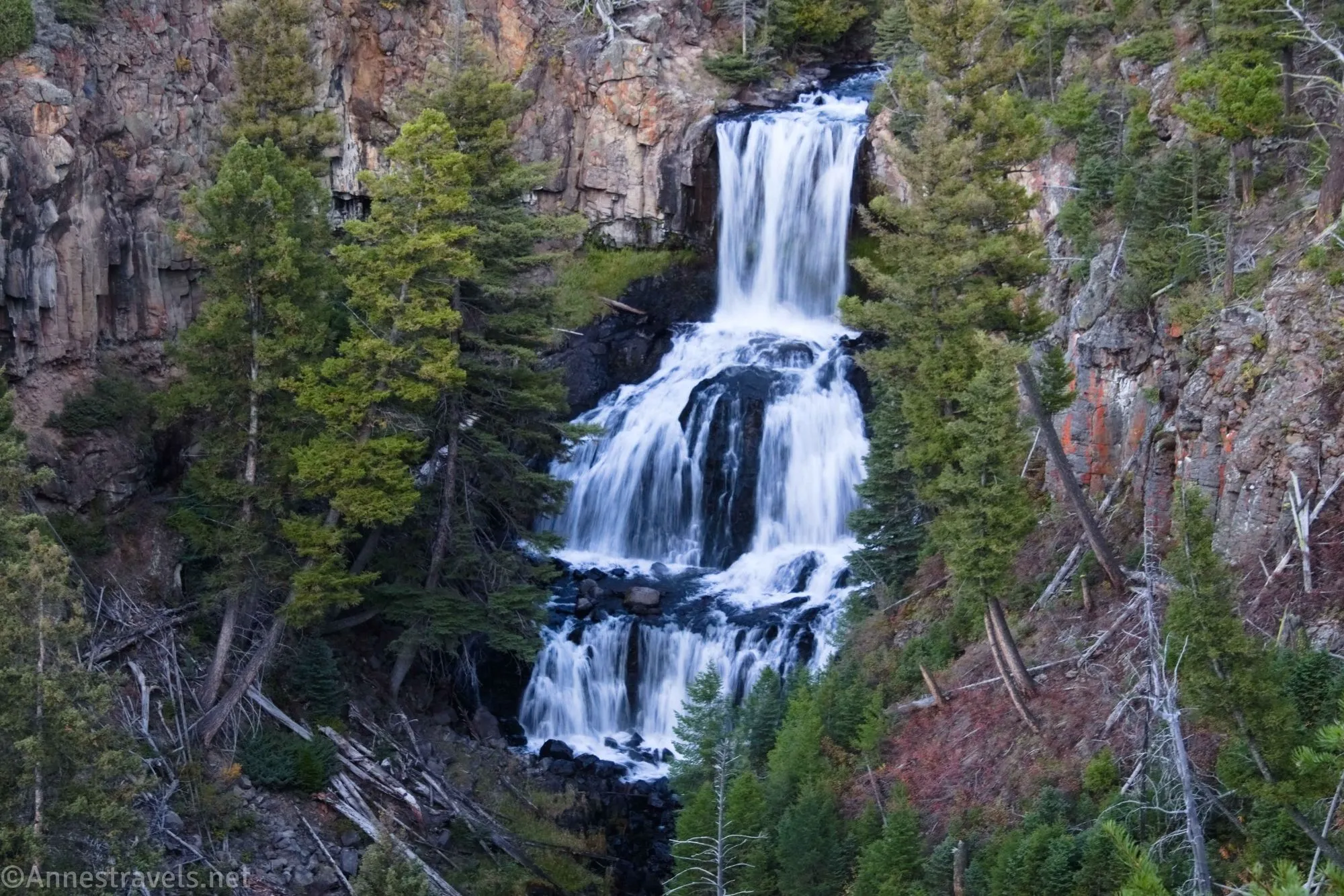 A silky waterfall tumbles between trees and rocky cliffs