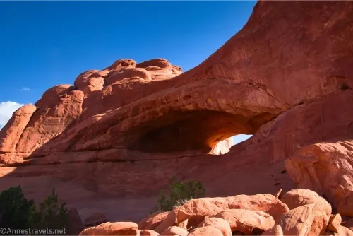 An arch in red slickrock with a red slickrock dome beyond