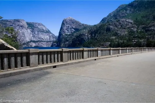 A concrete fence over a blue reservoir with rocky domes beyond
