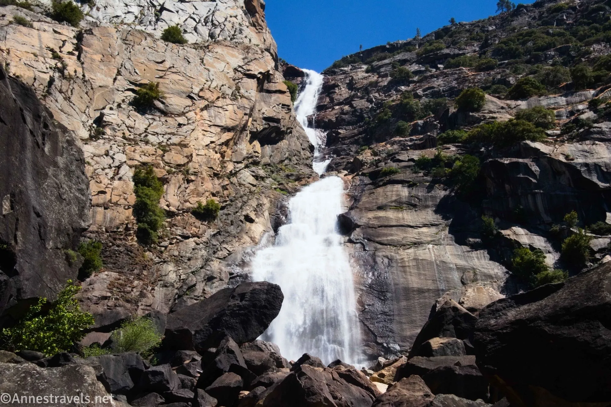 A waterfall tumbles in two tiers down a rocky cliff face