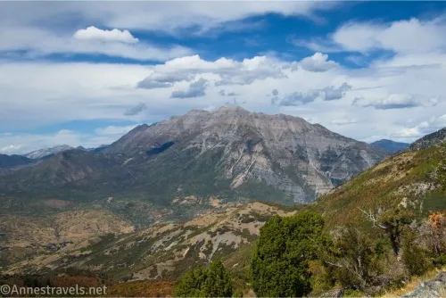A mountain rises out of a valley with clouds and blue sky overhead