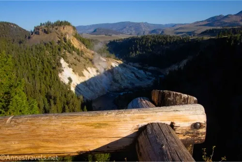 Hills rise over a river gorge beyond a wooden fence 