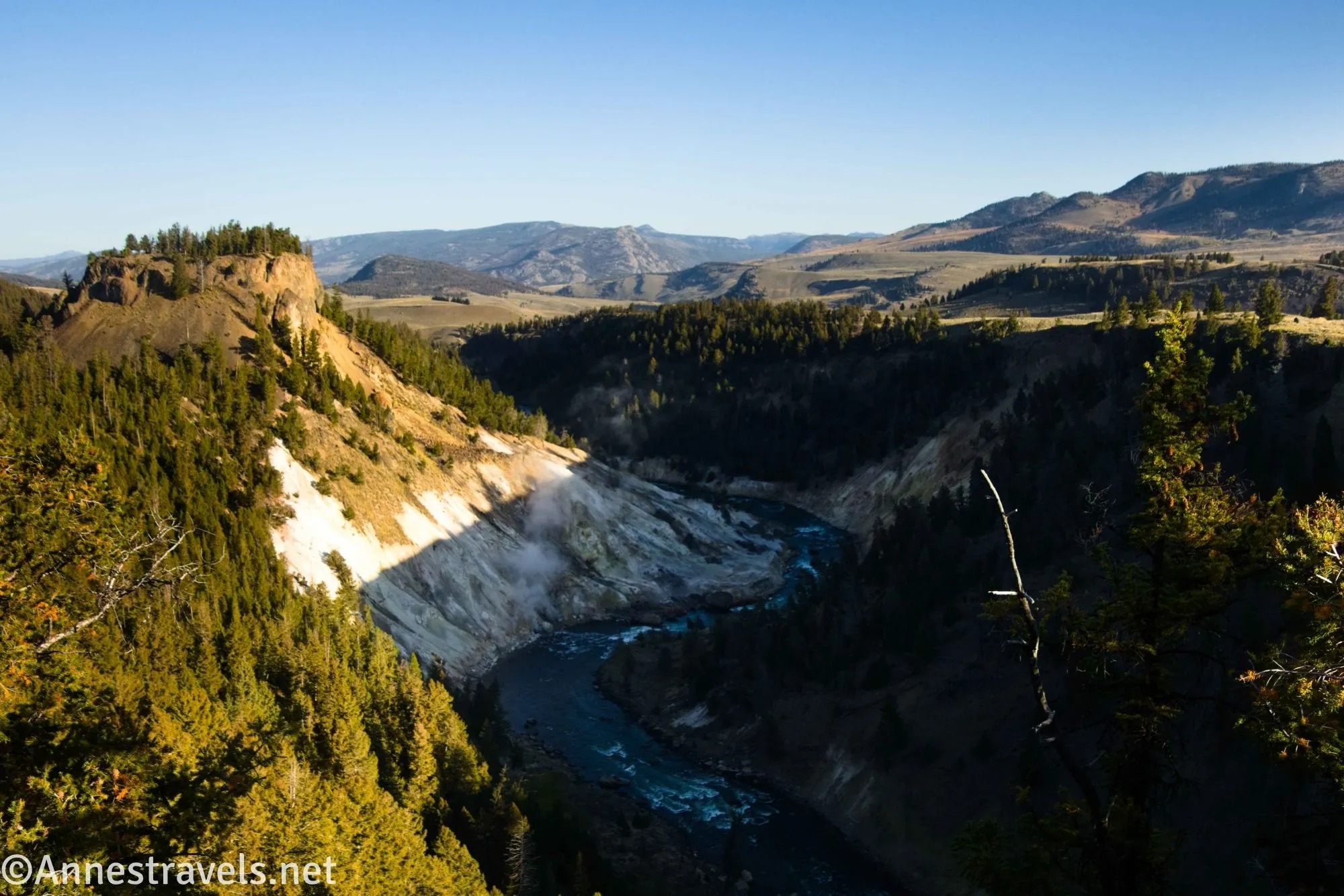 A hill rises to the left of a river gorge surrounded by hills and mountains 