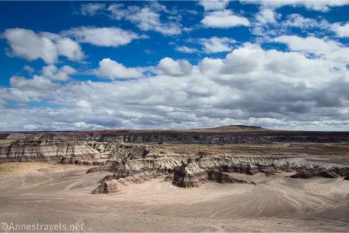Colorful striped badlands below puffy white clouds