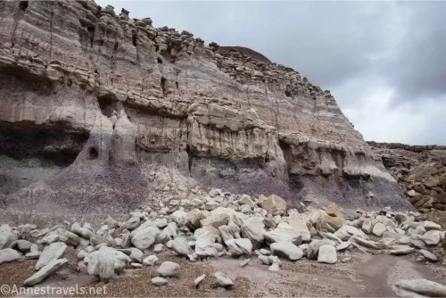 A badland wall with many white rocks at its base