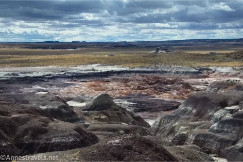 Badlands give way to grassy plains with clouds above