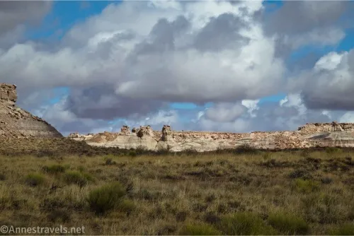 Clouds sail over rock formations in the sun and prairie in the shade