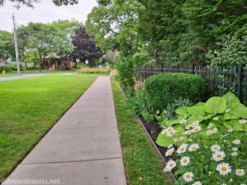 A sidewalk between a garden (and fence)