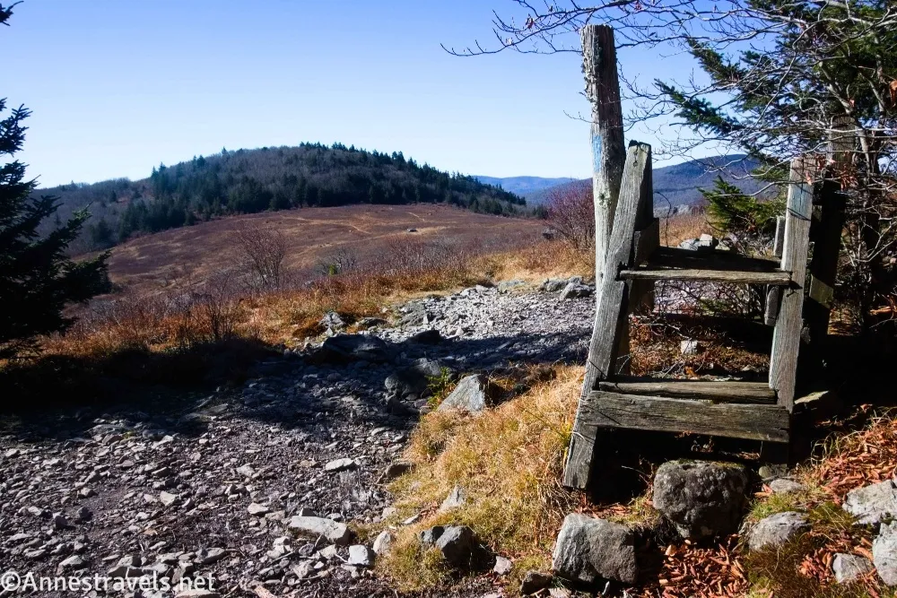 An old stile in a fence with meadows and hills beyond