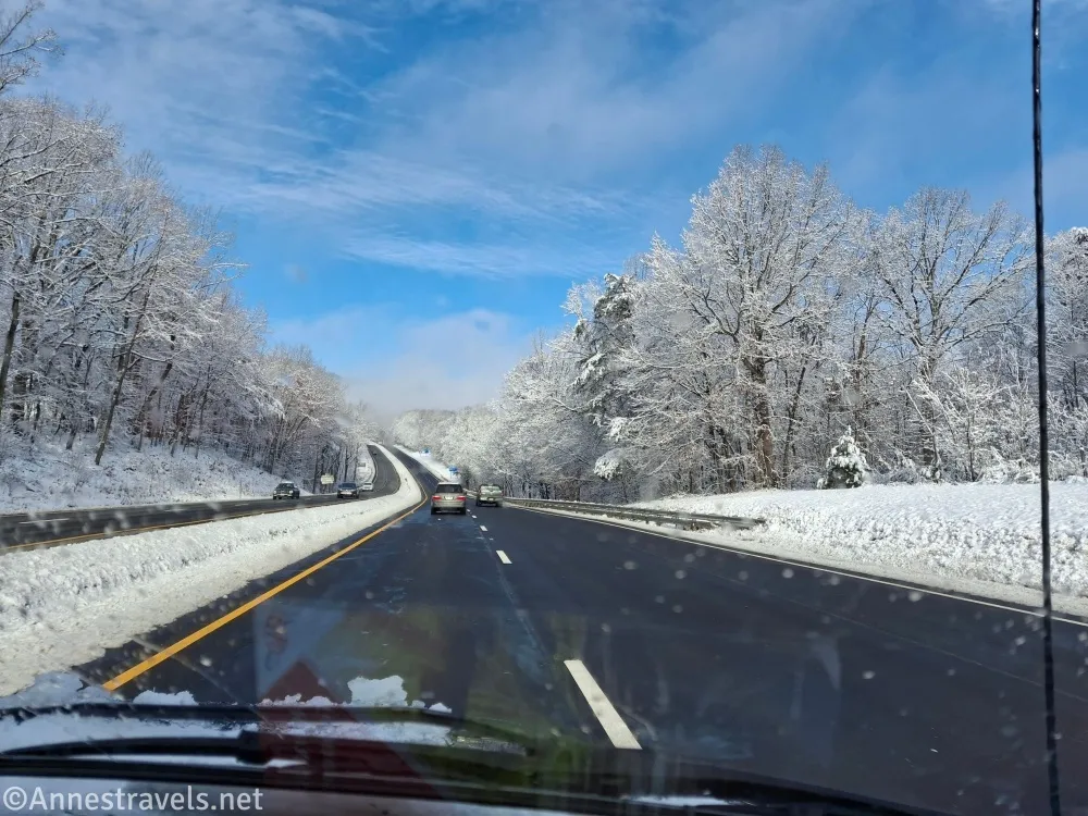 A road travels through a snowy landscape under a blue sky