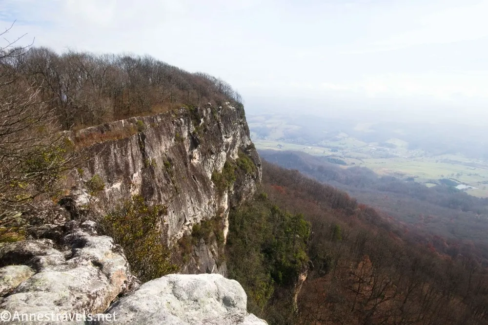 A cliff face above a valley with green fields