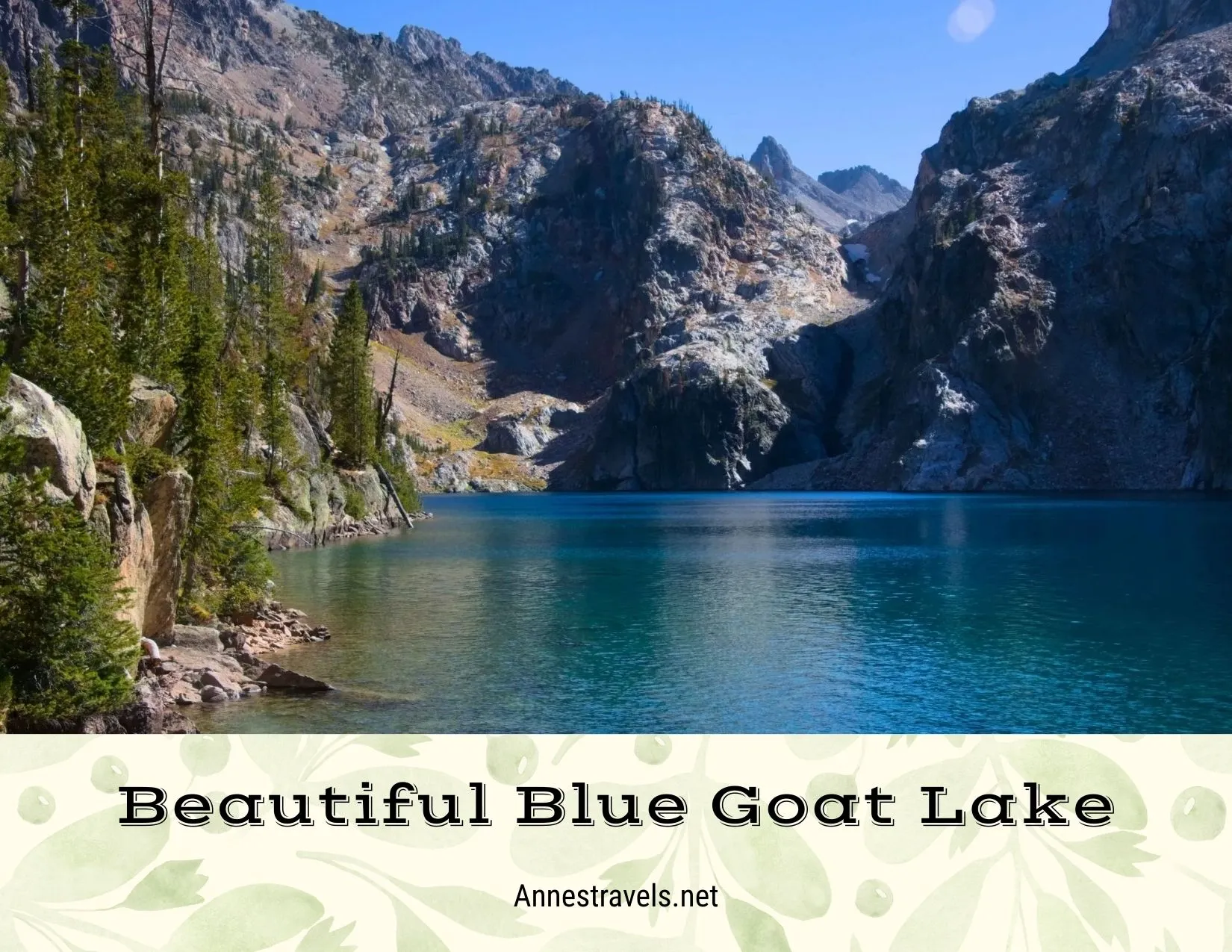 A blue lake below rugged rock walls and ringed with fir trees 