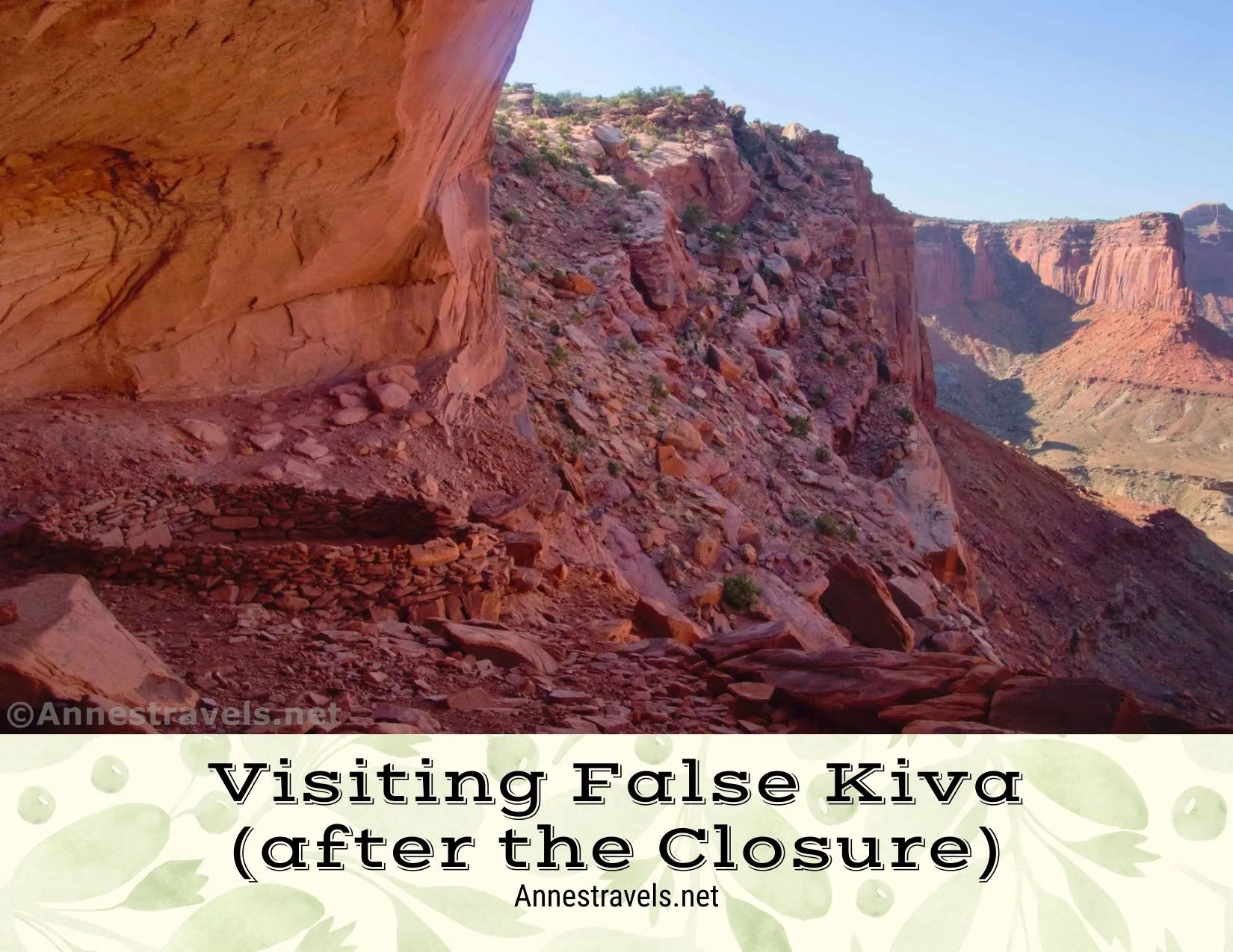 A circular rock shelter beneath a rock overhang with views out to red canyon walls 