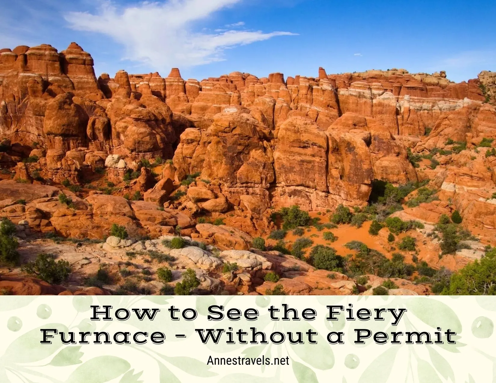 Red rock spires above a red sand and green bushes desert landscape 