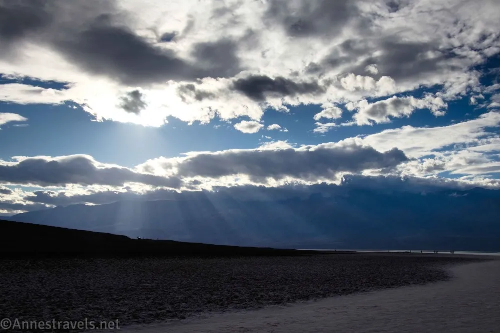 Clouds with sun streaming through it over a dark desert