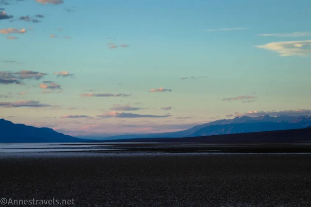 Sunset over a desert plain and lake with distant mountains and clouds