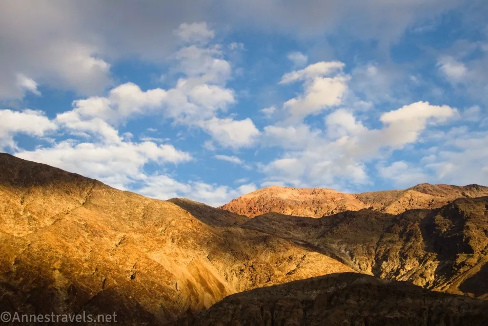 Colorful yellow and brown mountains below blue and cloudy skies