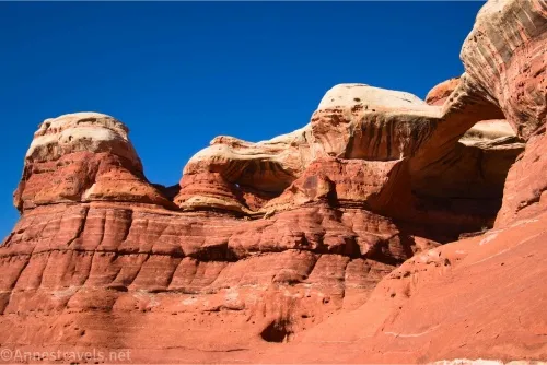 Red and white-topped cliffs with a couple of arches against the blue sky