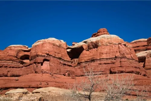 A red rock cliff with white rock on top and an arch between the two