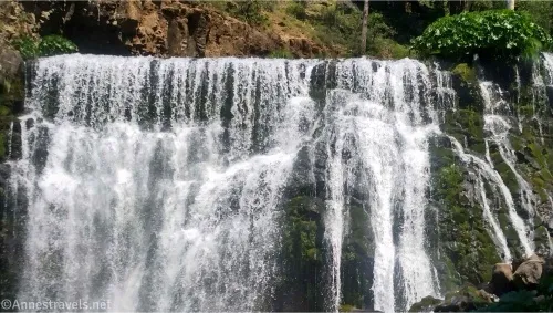 A large waterfall with moss and foaming water