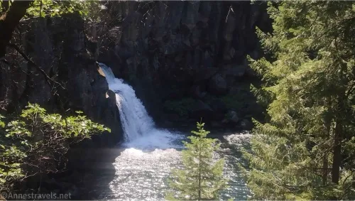 A waterfall appears from between cliffs surrounded by trees