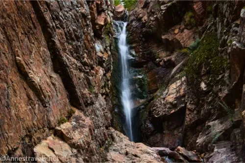 A waterfall tumbles over a ledge between layers of rock 