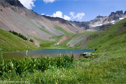 A lake in a meadow with rocky mountains above