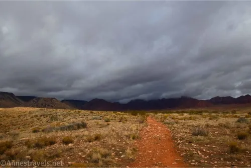 Dark clouds over a desert plain and a red trail 