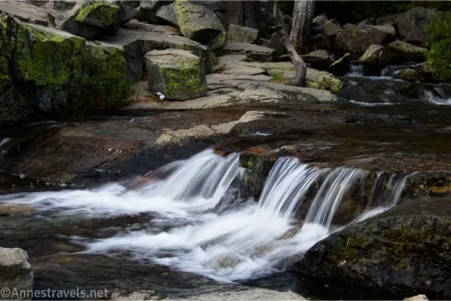 A small waterfall on a creek with rocks in the background