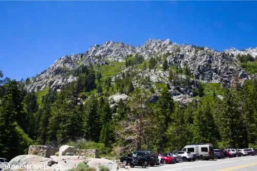 Cars parked below trees and cliffy mountains