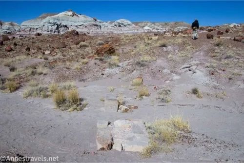 A slab of concrete in a wash with distant badlands and a hiker 