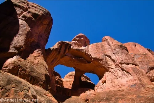 An arch high in a red cliff with two holes