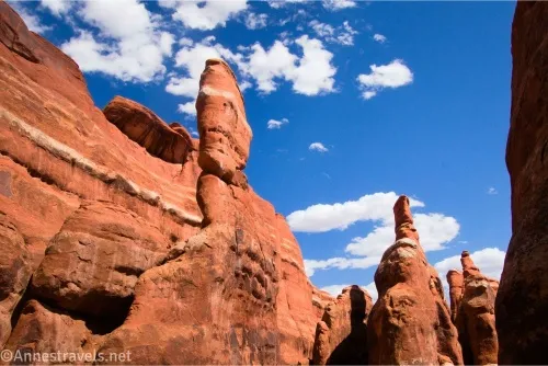 Clouds in a blue sky sail over red slickrock spires