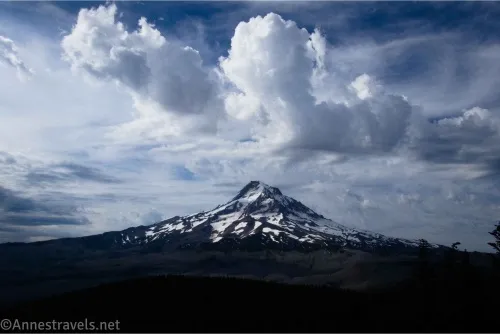 Puffy clouds over a snowy volcano and a dark foreground 