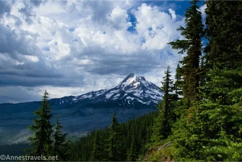 Dramatic clouds over a snowy volcano and a forest 
